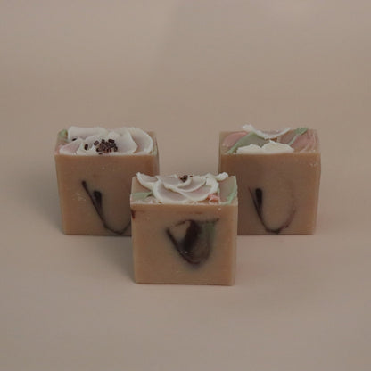 Three square soap bars with floral designs on a beige background