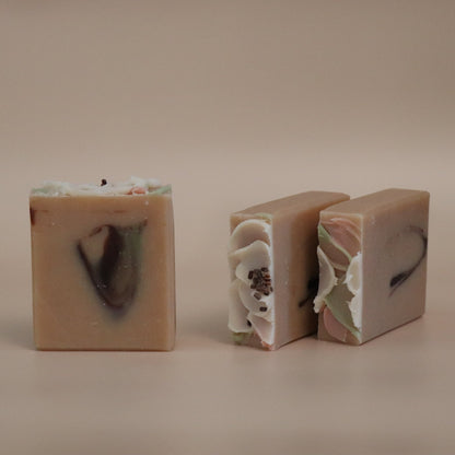 Three bars of soap with visible ingredients on a beige background