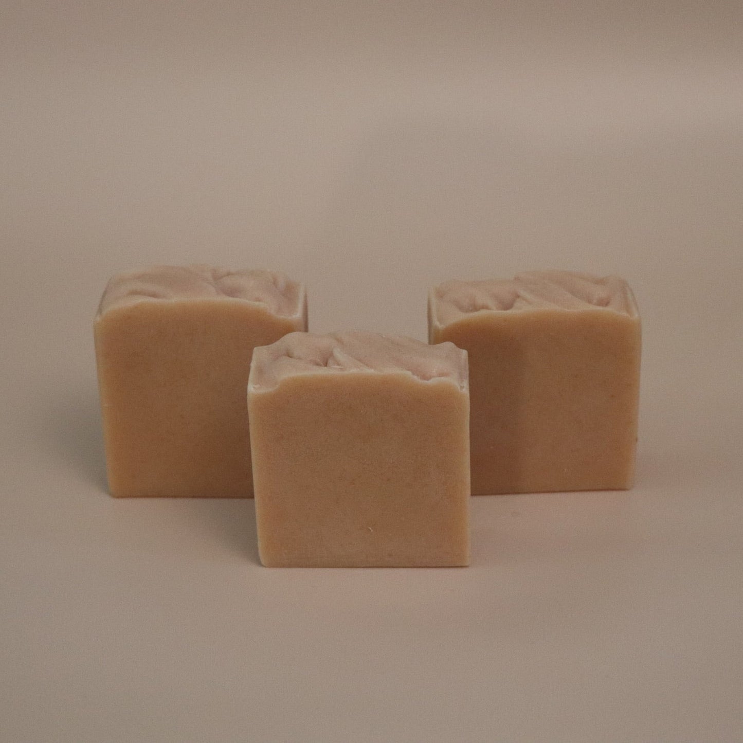 Three square beige bars of soap on a beige background
