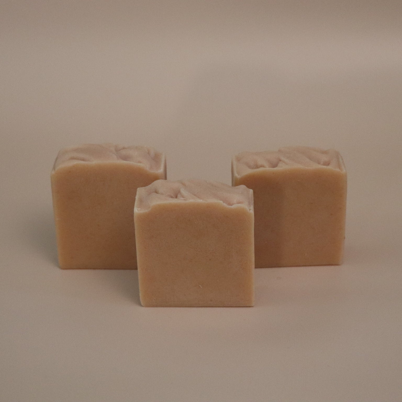 Three square beige bars of soap on a beige background