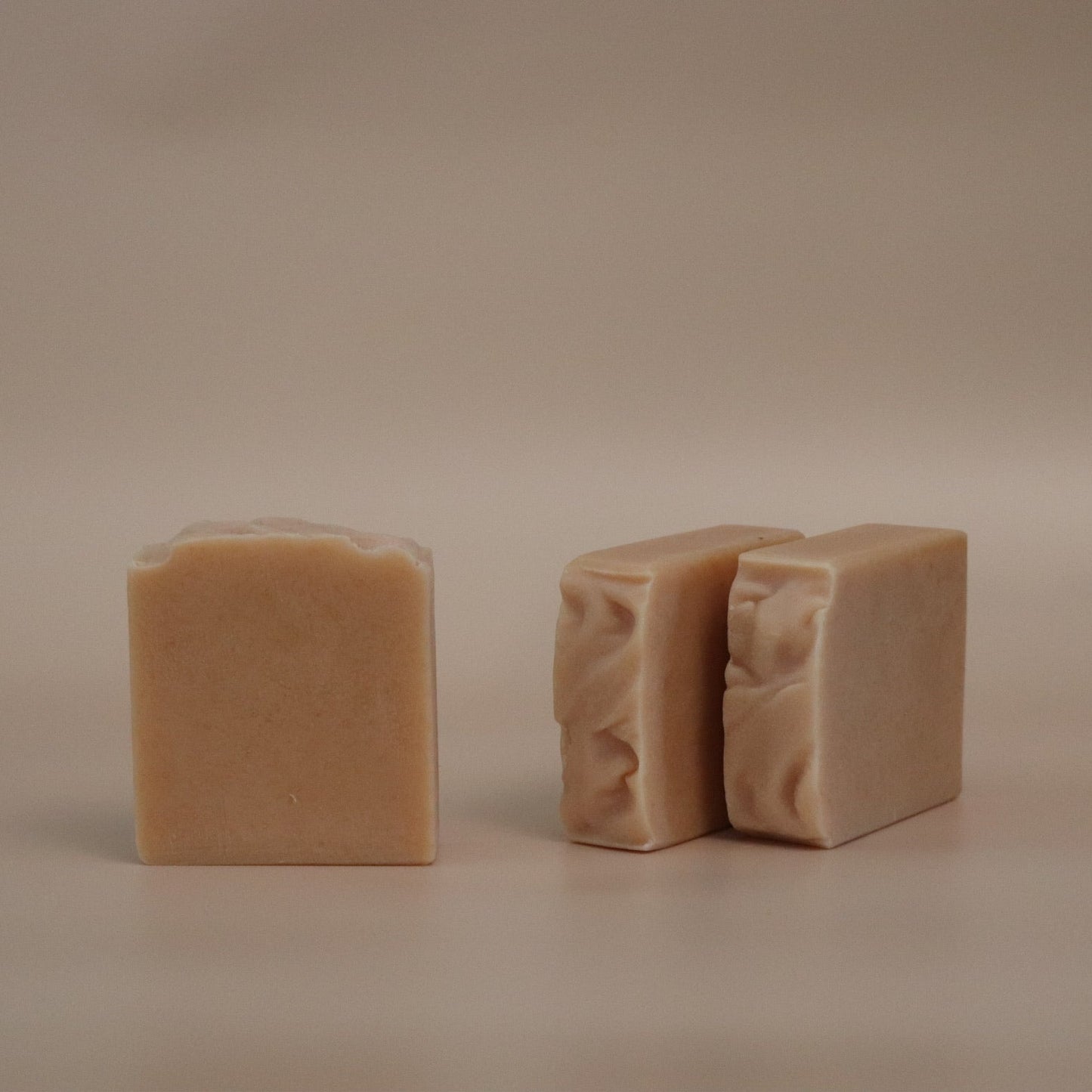 Two beige soap bars on a beige background
