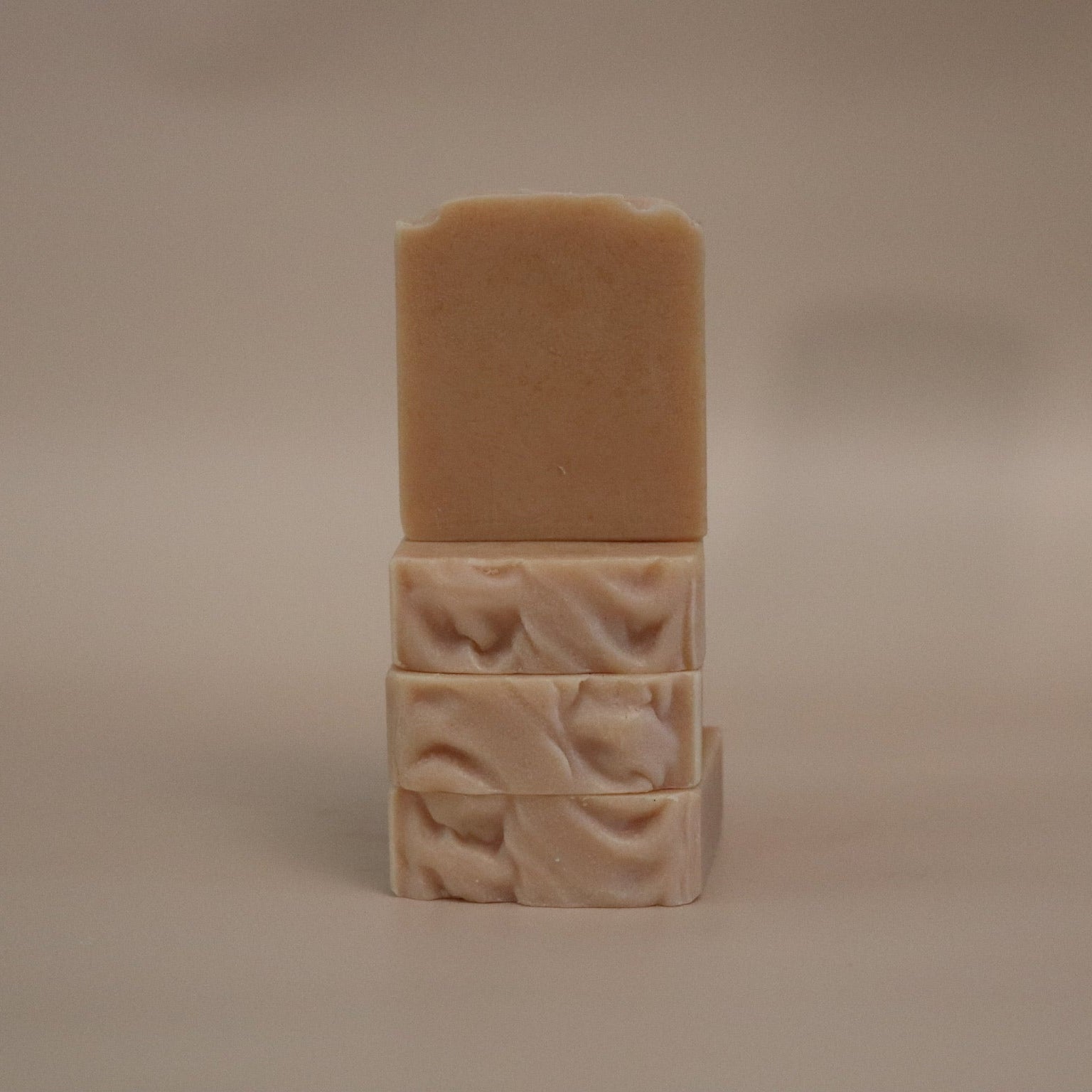Three stacked soap bars with textured surfaces on a beige background
