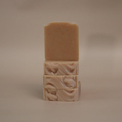 Three stacked soap bars with textured surfaces on a beige background