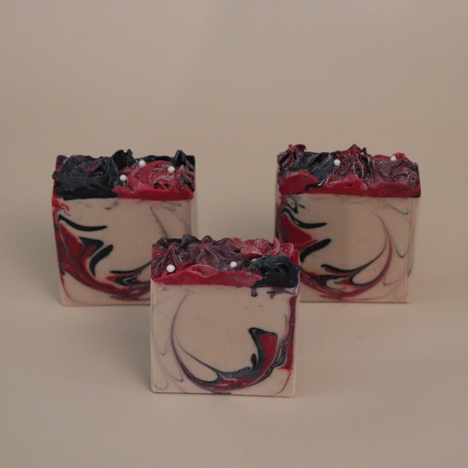 Three soap bars with a marbled design on a beige background