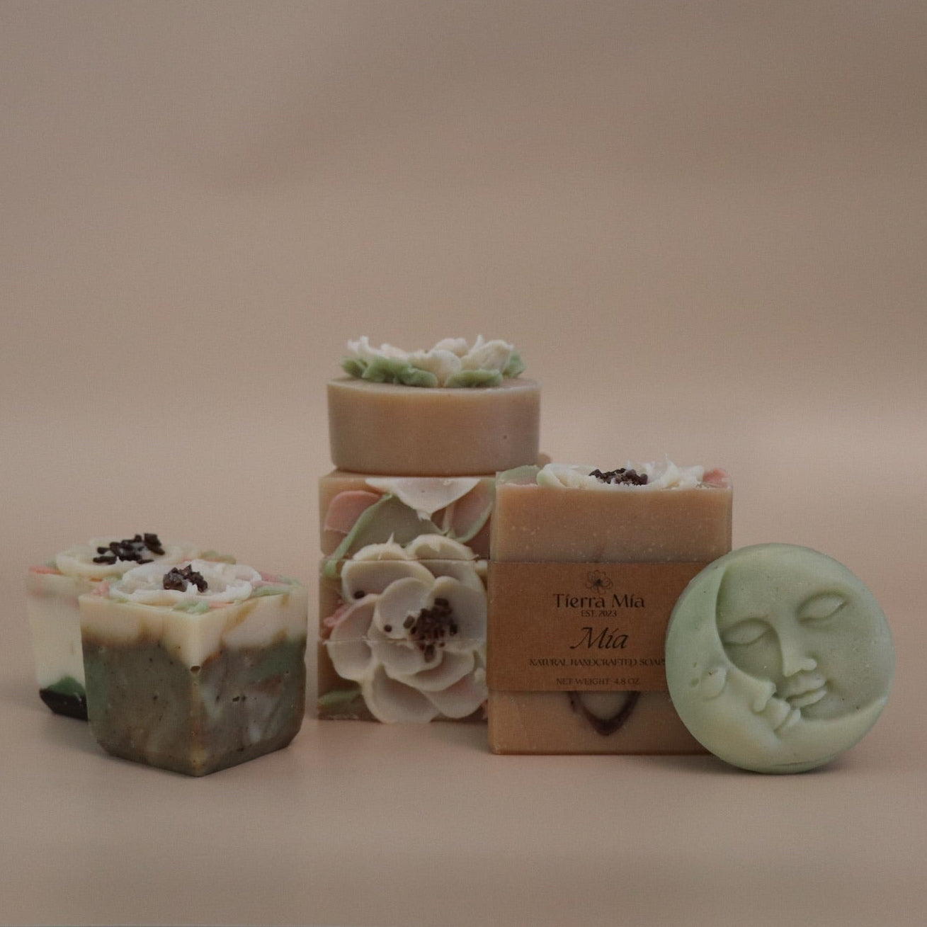 Collection of handmade soap bars with decorative designs on a beige background