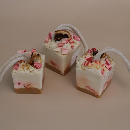 Three small square desserts with red and white floral toppings on a beige background