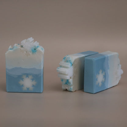 Two bars of soap with snowflake designs on a neutral background