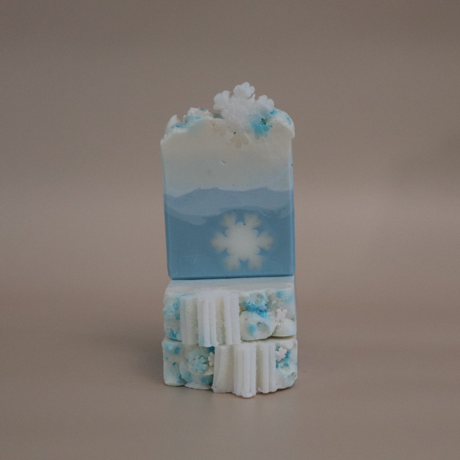 Stack of blue and white soap bars with snowflake design on a beige background