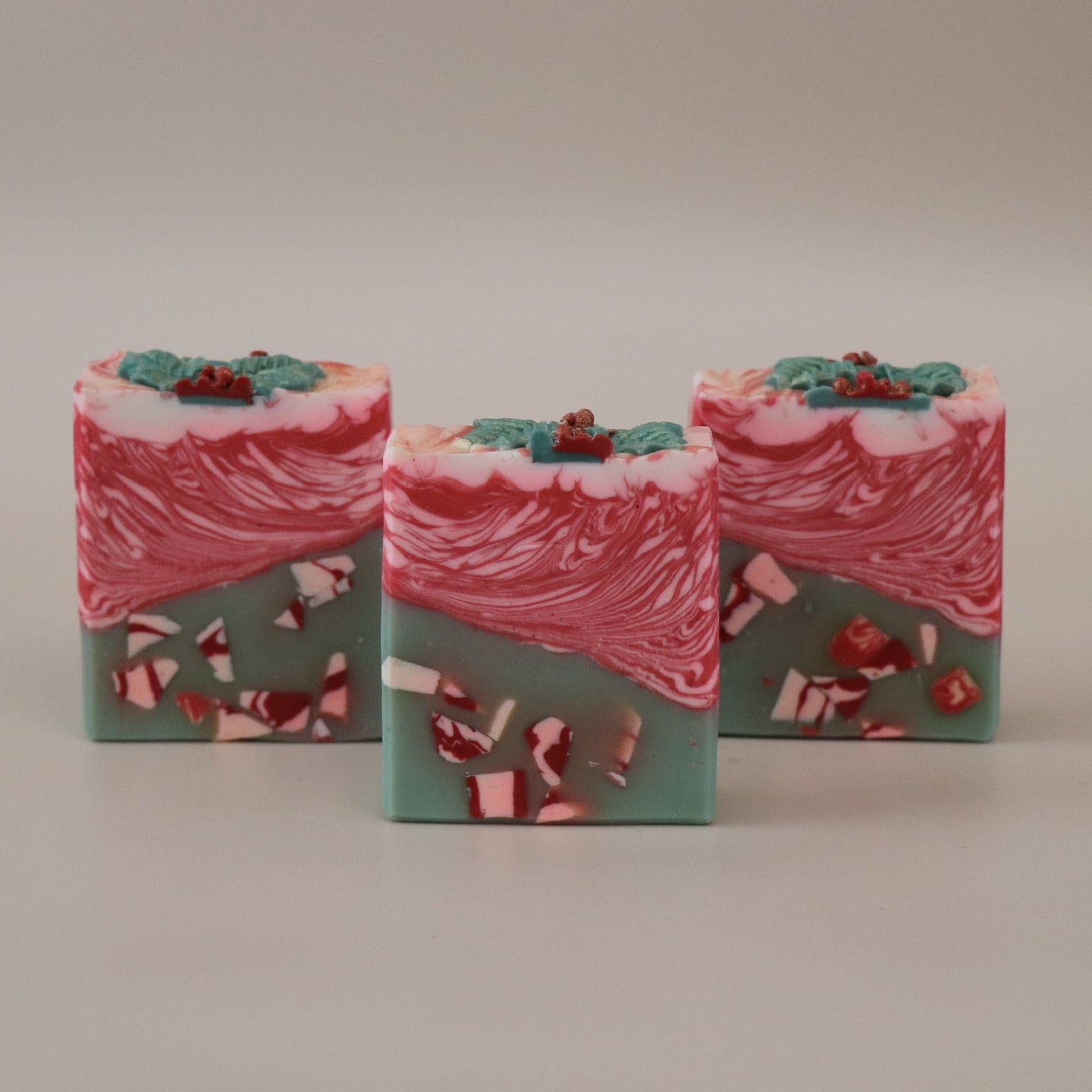 Three bars of soap with a red and green design on a beige background