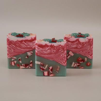 Three bars of soap with a red and green design on a beige background
