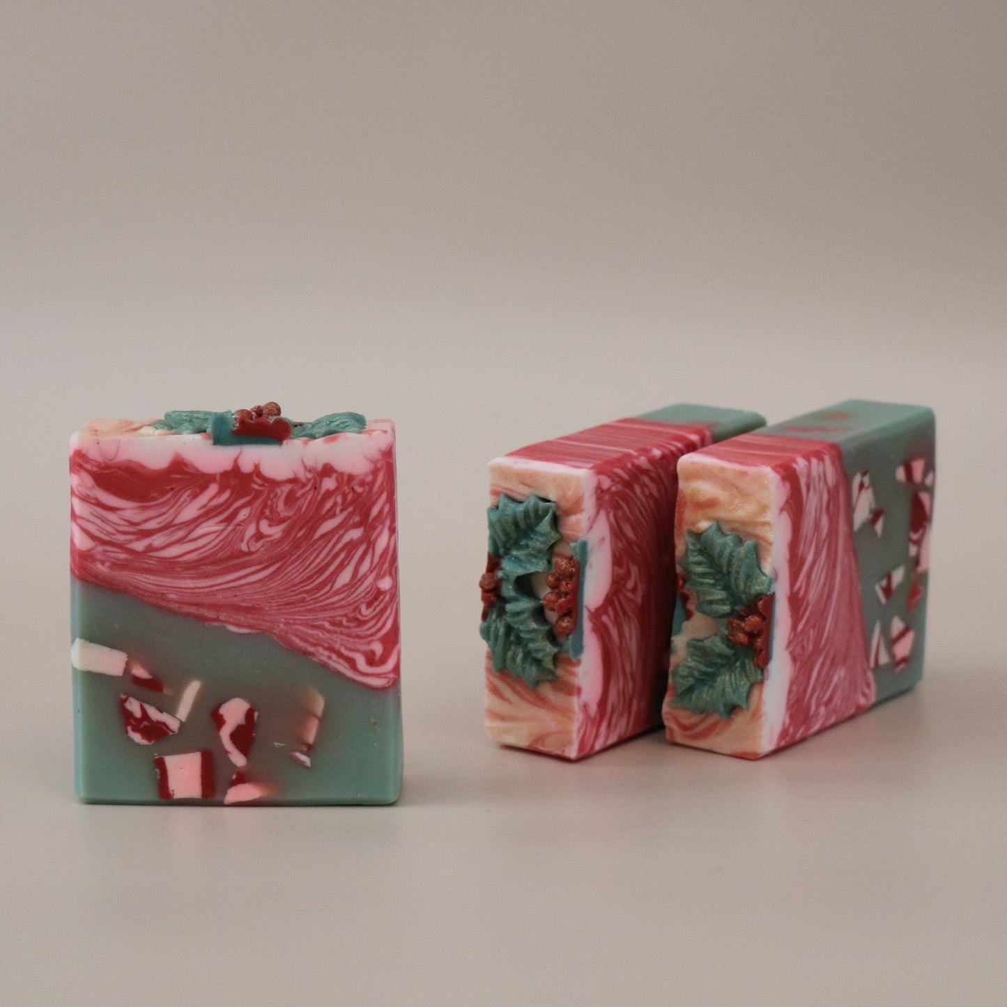 Three bars of soap with a red and green design on a beige background