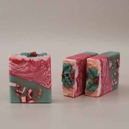 Three bars of soap with a red and green design on a beige background