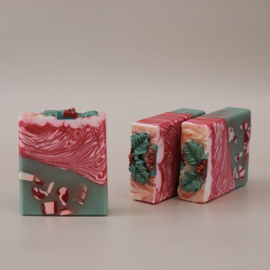 Three bars of soap with a red and green design on a beige background