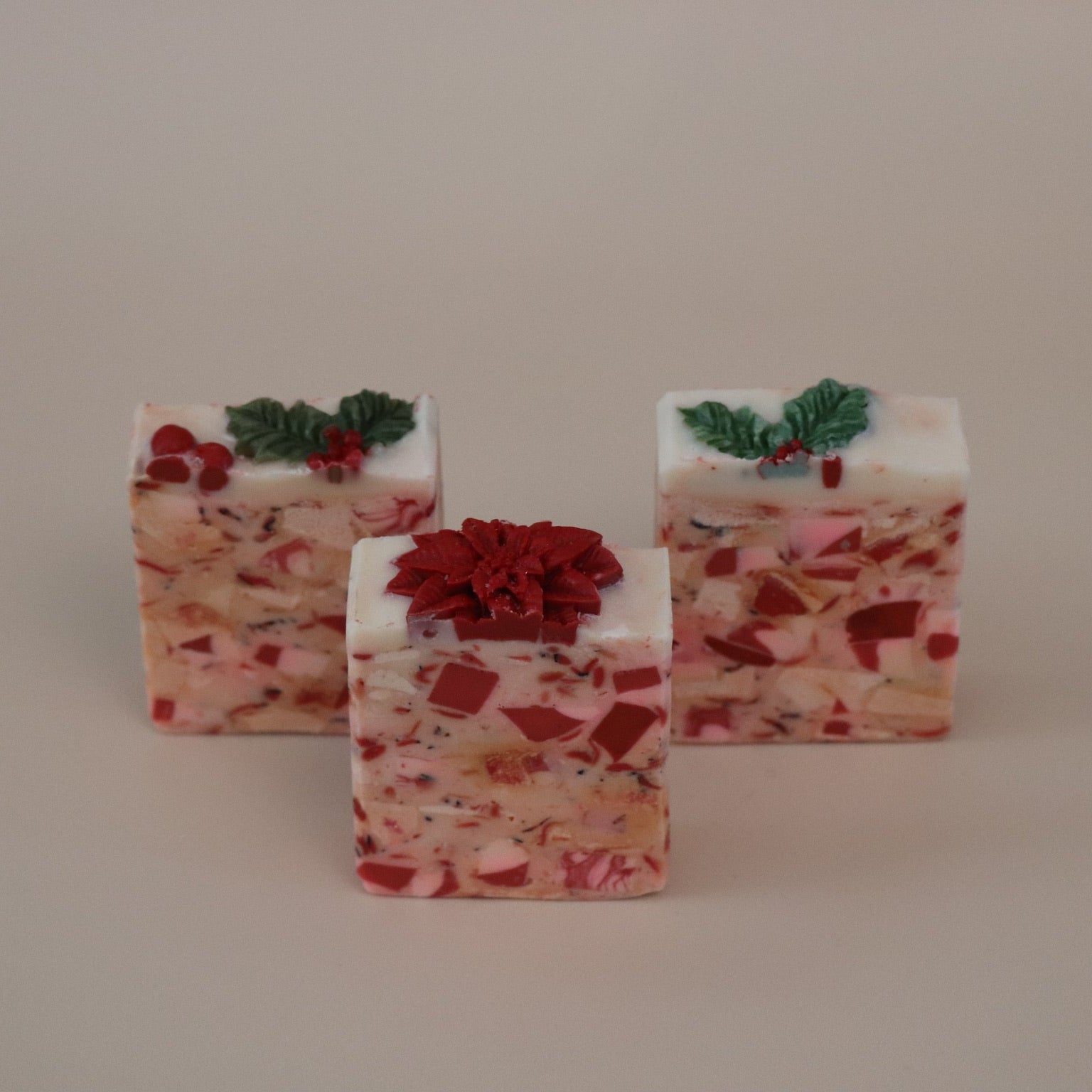Three soaps with red and green decorations on a beige background