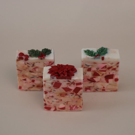 Three soaps with red and green decorations on a beige background