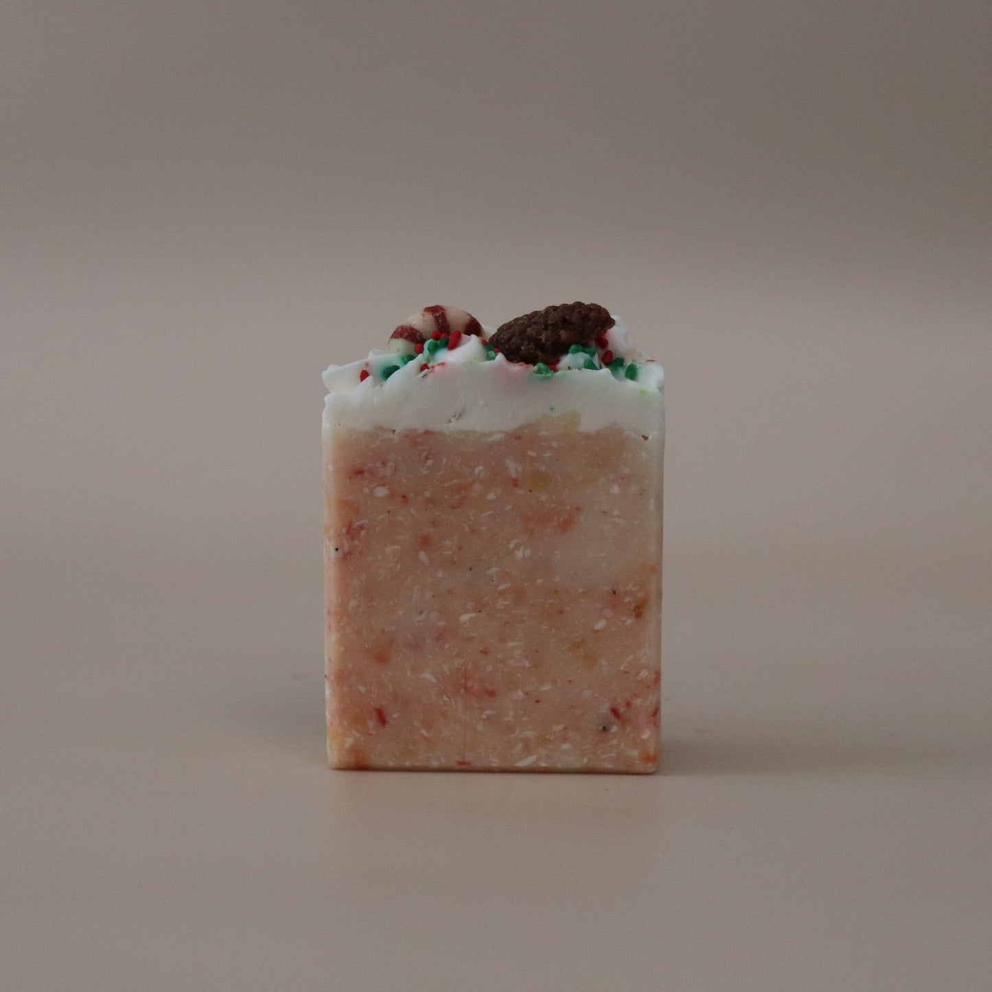 Square bar of soap with visible ingredients on a beige background