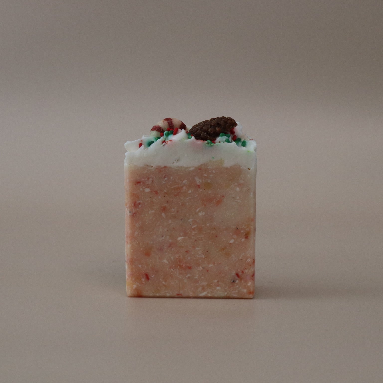 Square bar of soap with visible ingredients on a beige background