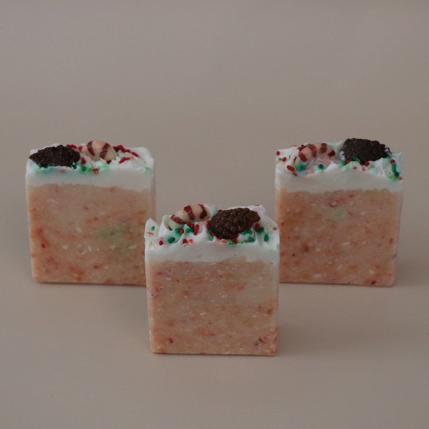 Three square-shaped candies with a orange and white color scheme on a beige background