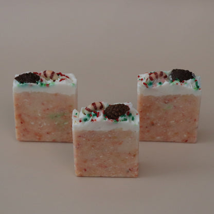 Three square-shaped candies with a orange and white color scheme on a beige background