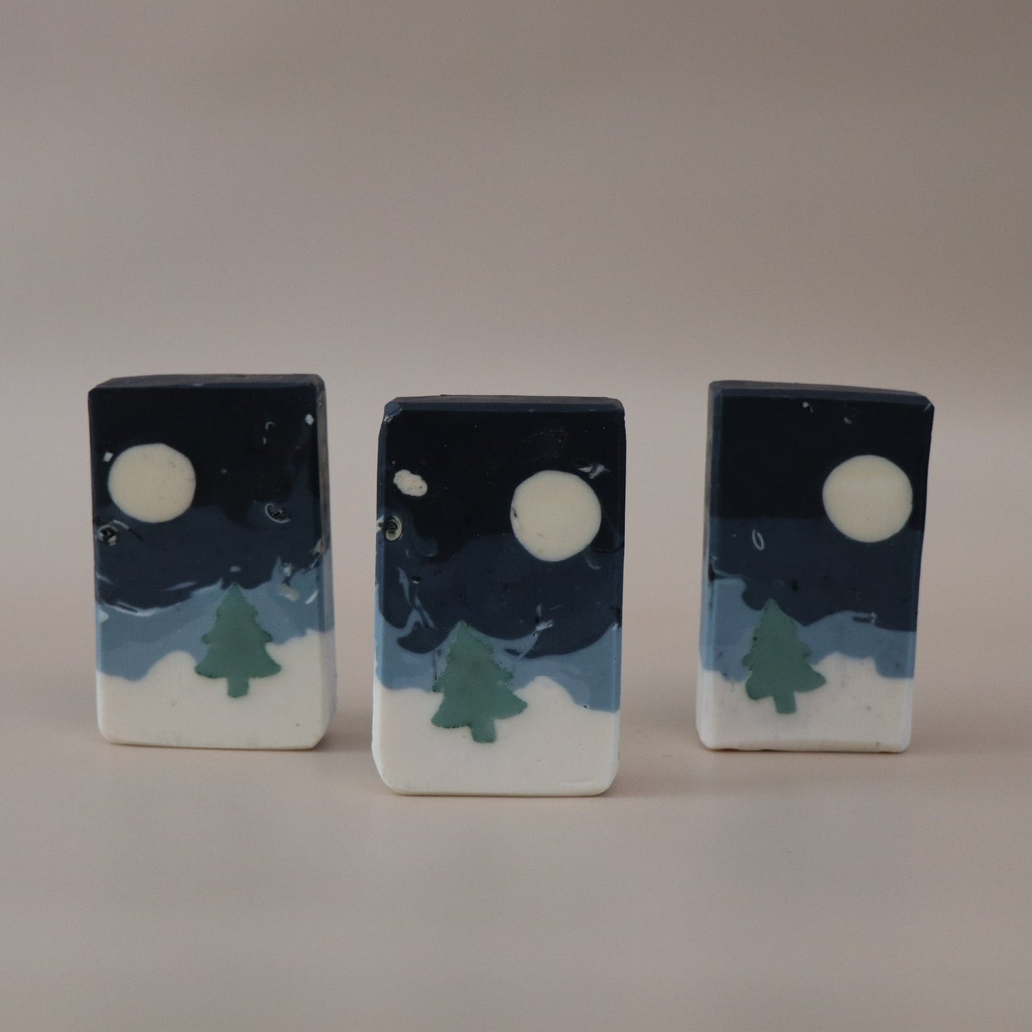 Three rectangular soap bars with moon and tree designs on a beige background