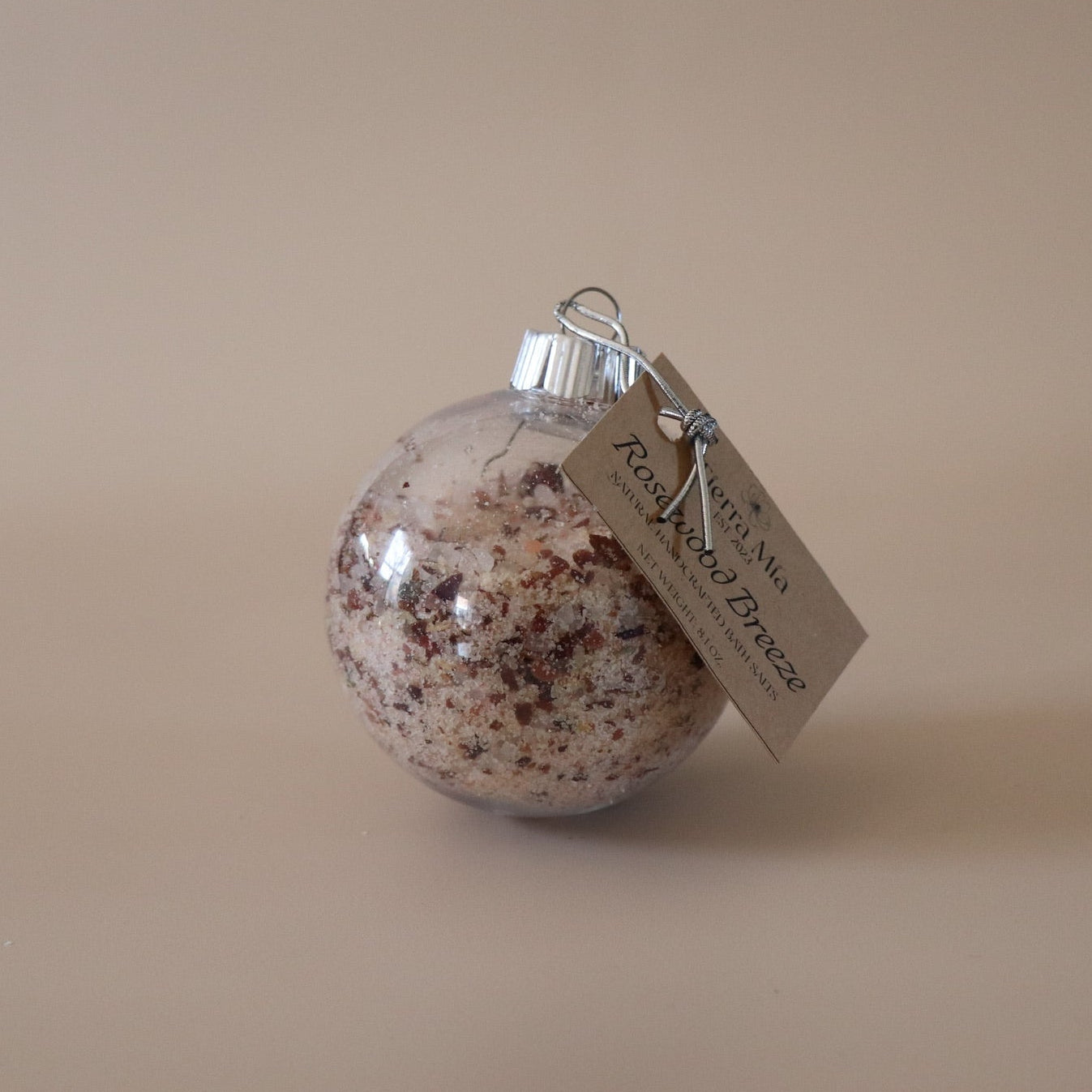 Decorative ornament with a speckled interior and a tag on a beige background