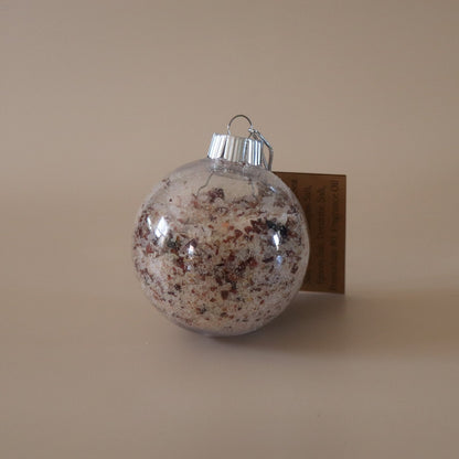 Clear Christmas ornament with decorative elements on a beige background