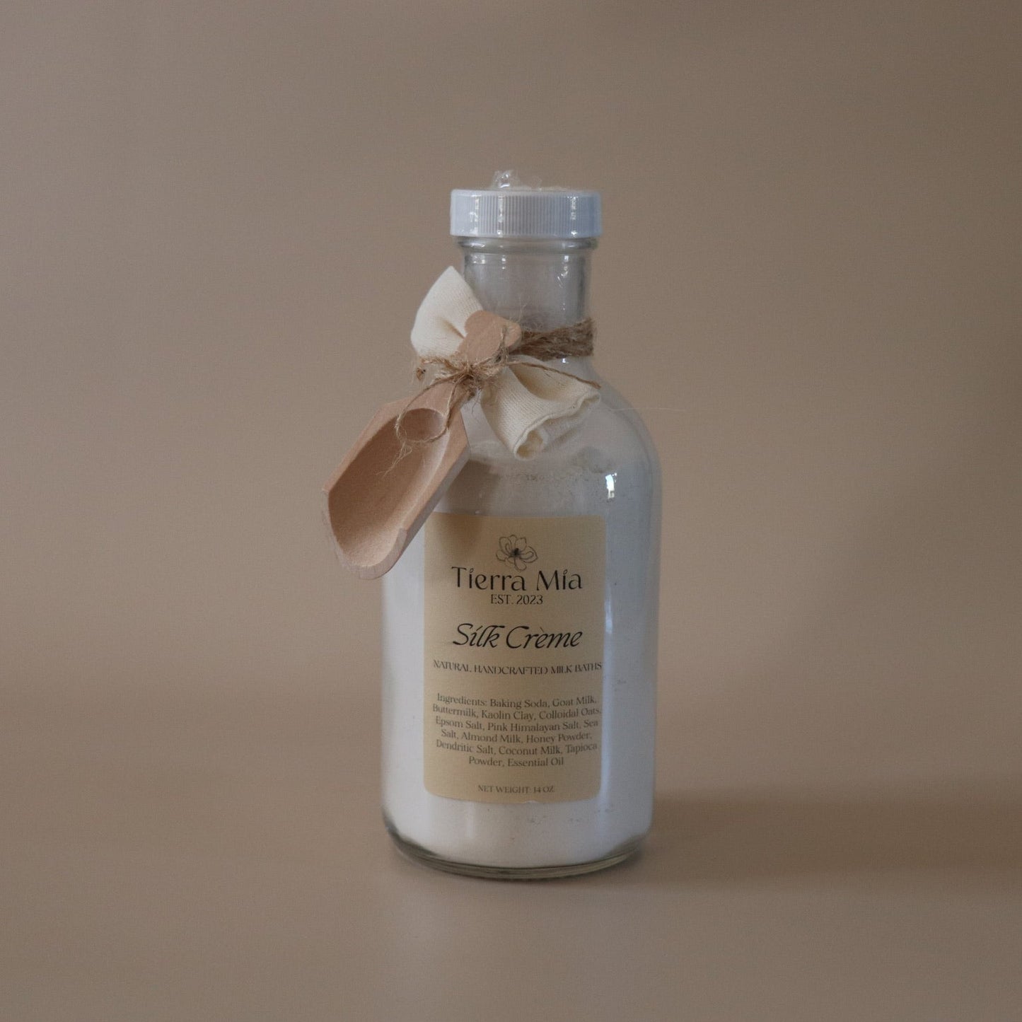 Bottle of Tierra Mia Silk Creme with a wooden spoon on a beige background