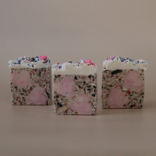 Three square-shaped soaps with floral and pink designs on a beige background